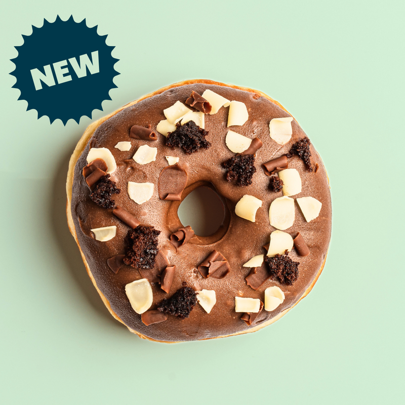 Load image into Gallery viewer, Chocolate ring doughnut with milk &amp; white chocolate curls and brownie pieces on a light green background, featuring a &#39;NEW&#39; label.
